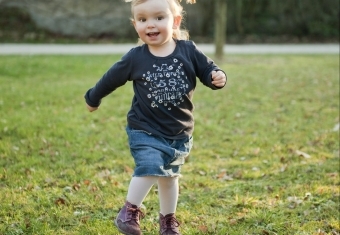 Pige med blå kjole løber på græsset