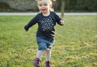 Pige med blå kjole løber på græsset