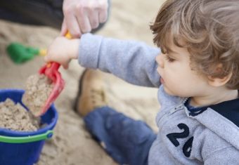Dreng skovler sand op i en spand